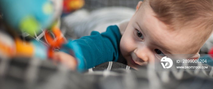 Cute baby boy stretches out his hand towards the camera in front and tries to reach and touch the toy. Front angle view