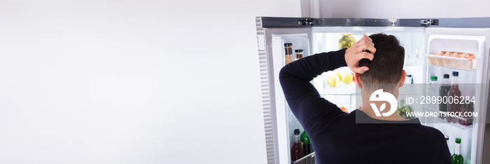 Confused Man Looking At Food In Refrigerator