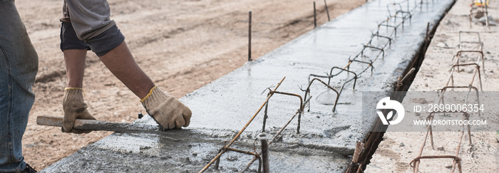 Construction worker is leveling concrete pavement at road construction site.