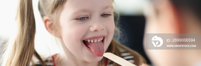 Doctor examines throat of little girl closeup