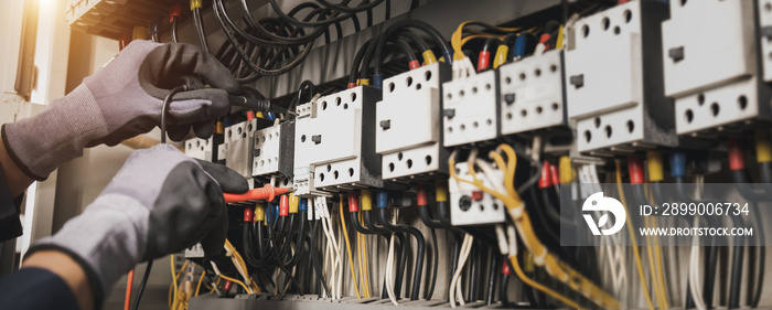 Electricity and electrical maintenance service, Engineer hand holding AC multimeter checking electric current voltage at circuit breaker terminal and cable wiring main power distribution board.