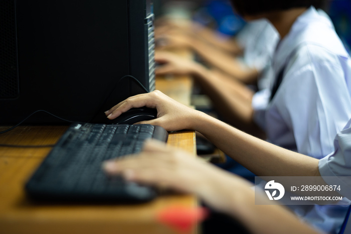 Side view of asian uniform students in computer classroom.