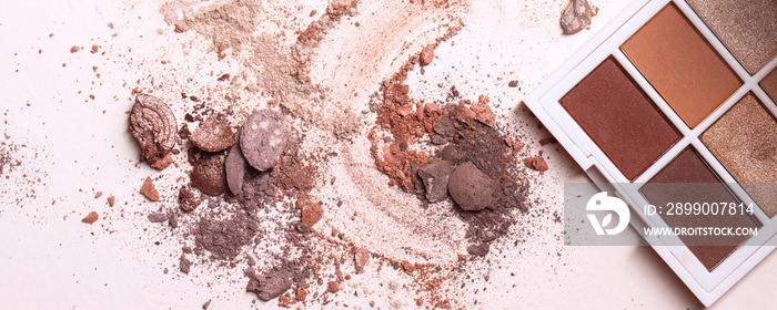 Crushed eyeshadows and eyeshadow palet. Macro texture of make-up on beige background