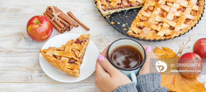 Girl with a cup of tea and a pie with apples and cinnamon. Selective focus.