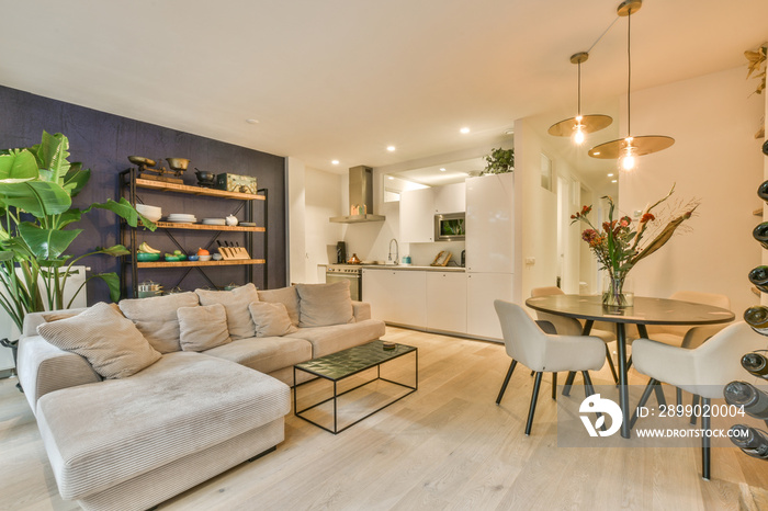 a living room with white walls and wood flooring, there is a small dining table in front of the couc