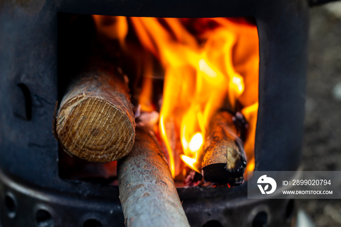 A burning outdoor mini stove, used for heating up tea - close up