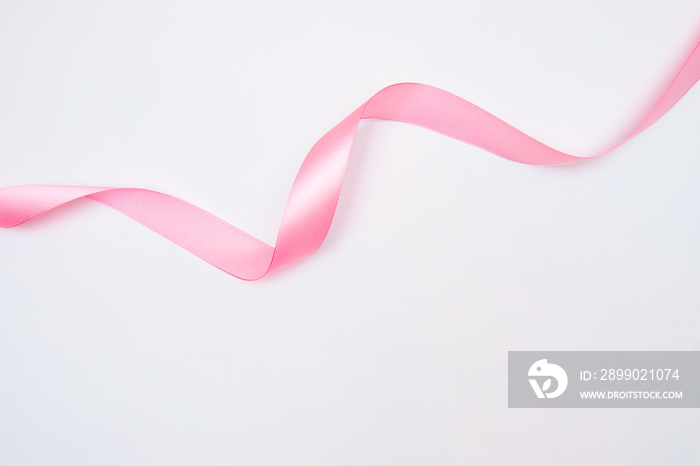 Curled pink ribbon with highlights isolated on white background, top view