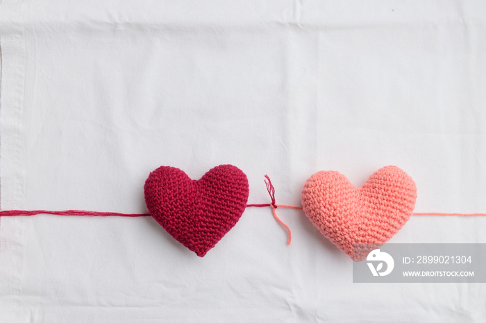 Two crocheted amigurumi pink hearts connected with a knot on a white background. Valentines banner 