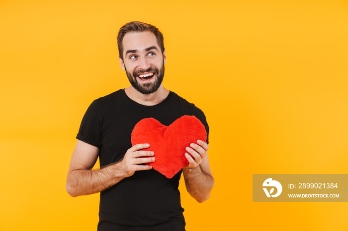Image of romantic man wearing t-shirt smiling and holding red paper heart