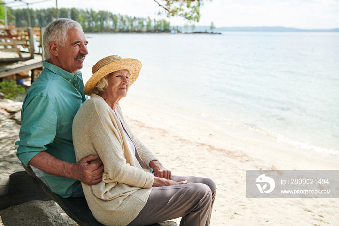 Senior romantic man and woman sitting on the beach