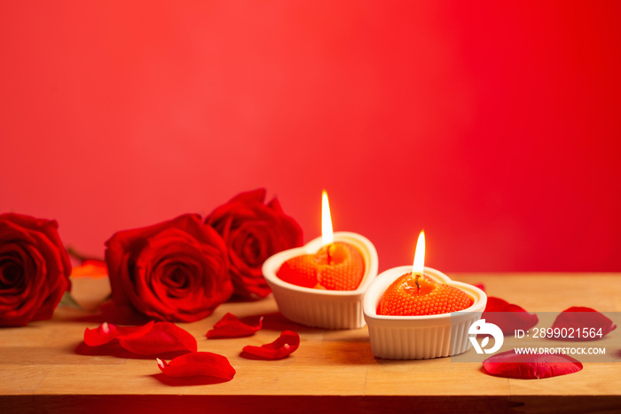 red roses with burning candles on red background