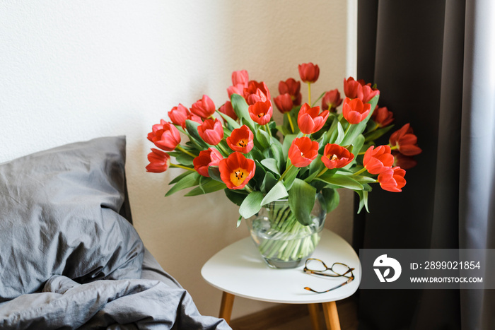 Huge bouquet of red tulips in a vase on the table.