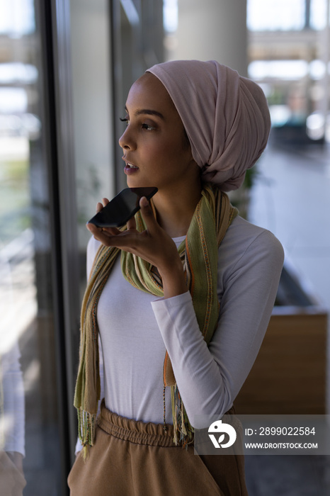 Young mixed-race female executive talking on mobile phone in modern office