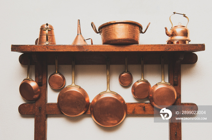 Old fashioned copper cookware pots pans aligned  on wood shelf