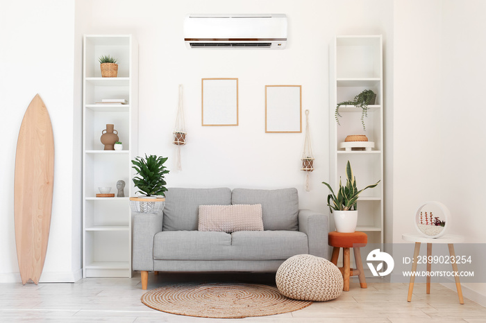 Interior of light living room with wooden surfboard, sofa, shelf units and air conditioner