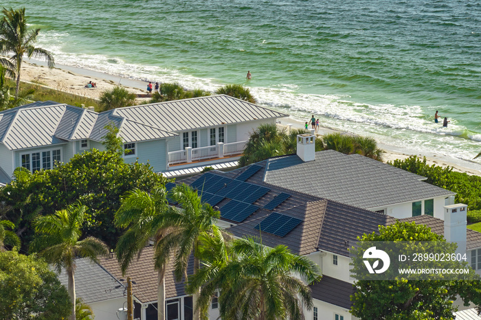 Aerial view of seaside expensive american home roof with blue solar photovoltaic panels for producin