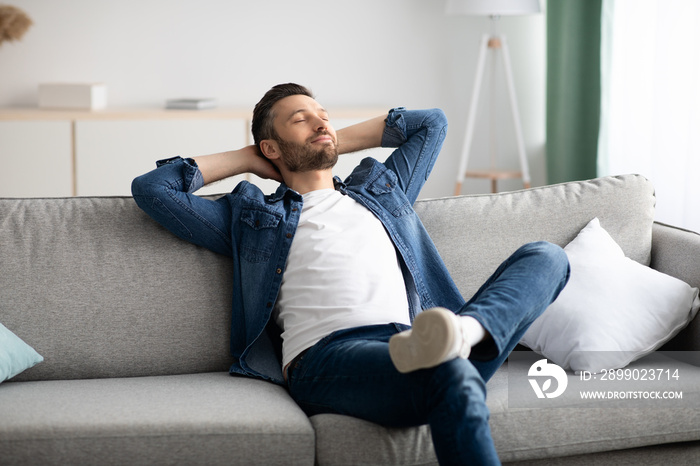 Happy bearded man relaxing on sofa at home