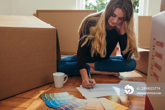 Woman making a list of articles sitting on floor with shade card