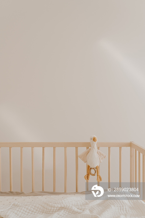 Wooden baby room furniture. Bed crib, toy duck, muslin blanket. Baby bedroom modern interior with wh