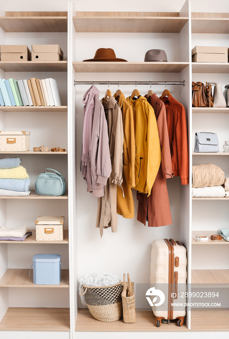 Big wardrobe with different clothes and accessories in dressing room