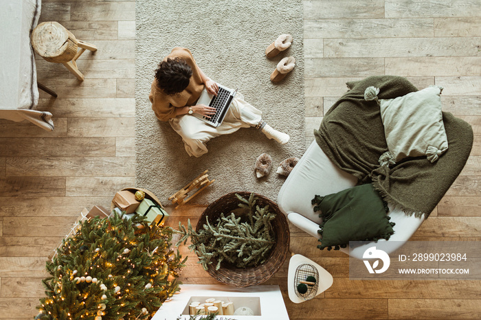 Christmas / New Year decorated home living room. Beautiful woman working on laptop. Decorated Christ