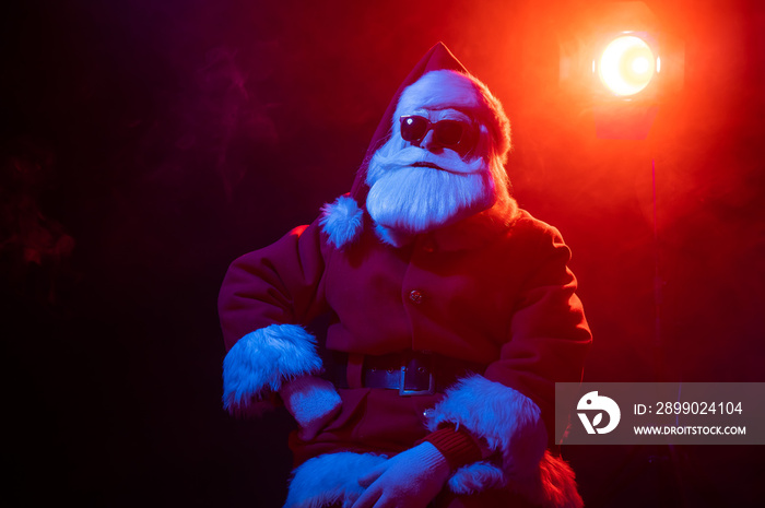 Santa claus in sunglasses in neon light on a black background. Christmas party.