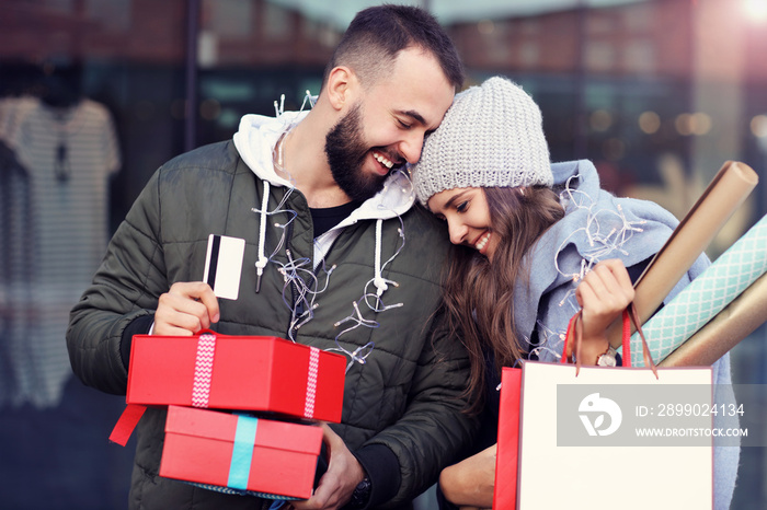 Portrait of happy couple with shopping bags after shopping in city