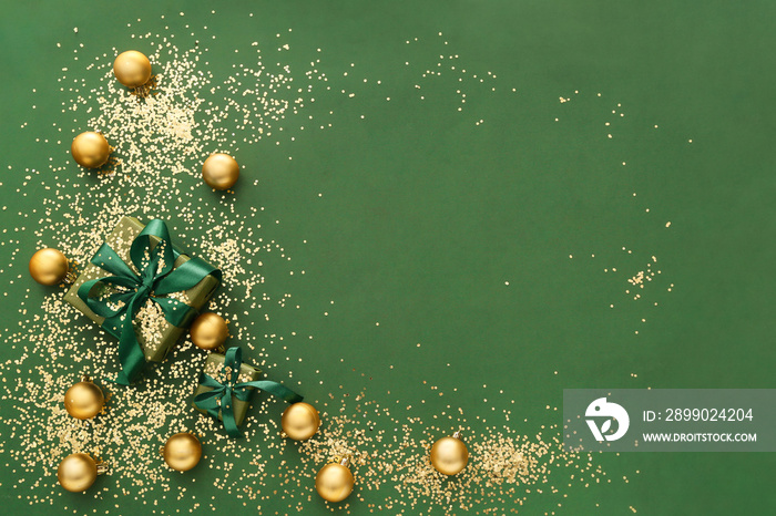 Frame made of golden confetti with gift boxes and Christmas balls on green background