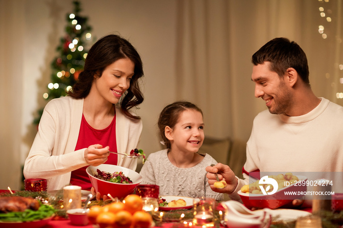 holidays, family and celebration concept - happy mother, father and little daughter having christmas