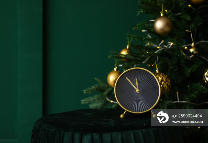 Stylish alarm clock on blurred Christmas tree background