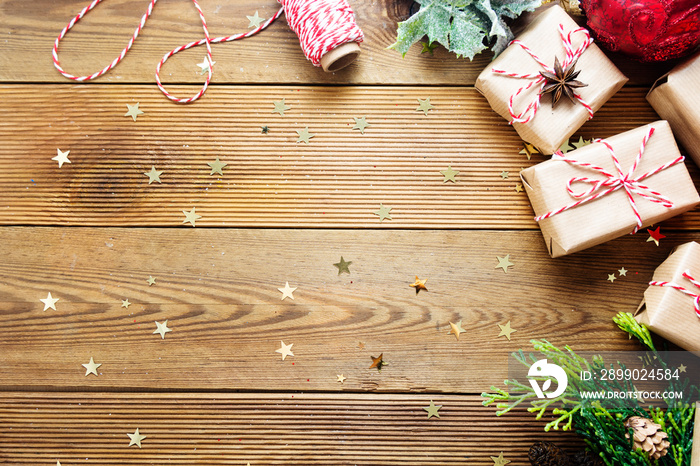 Christmas mock up, gift boxes wraped in craft paper, fir branches, red baubles, pine cones over wood