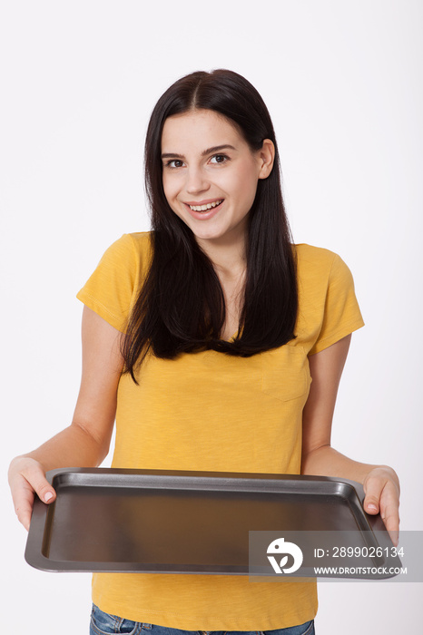 Young attractive woman holding an empty tray isolated on white background. Woman in yellow T-shirt f