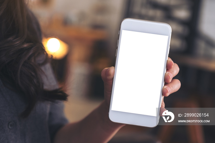 Mockup image of a woman holding and showing white mobile phone with blank screen in cafe