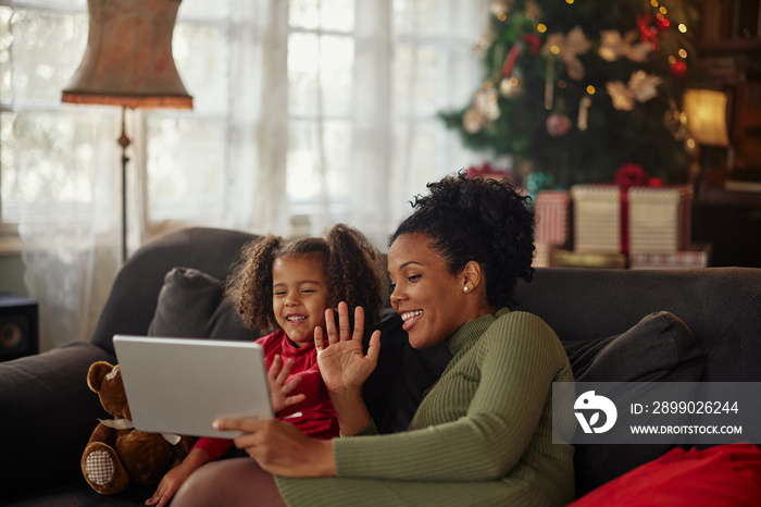 African american mother and daughter having video call via tablet at home