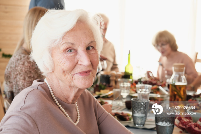 Portrait of senior woman with white hair looking at camera she has dinner with her family at the tab