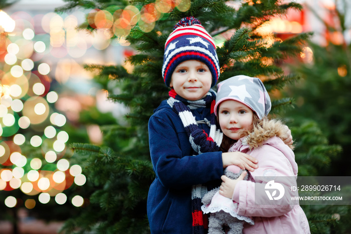 Two little smiling kids, preschool boy and girl hugging on German Christmas market. Happy siblings c