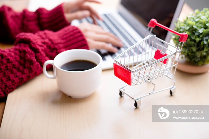 Shopping cart and hand using laptop computer on table,online shopping concept