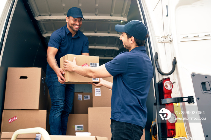 Two happy couriers unloading packages from the car