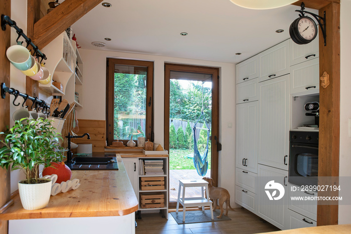 Interior of kitchen in cottage with white wooden furniture and big window. Rustic style with vintage