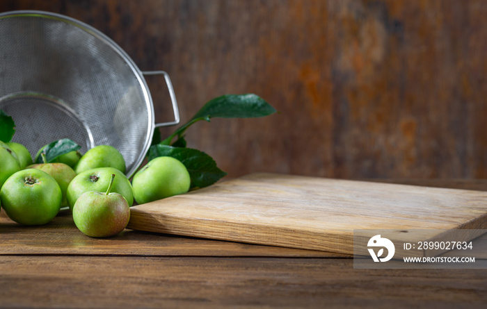 Kitchen table with empty cutting board and green apples. Place for your object