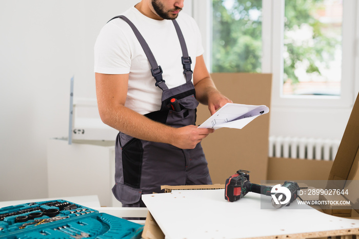 handyman reading user manual while assembling kitchen