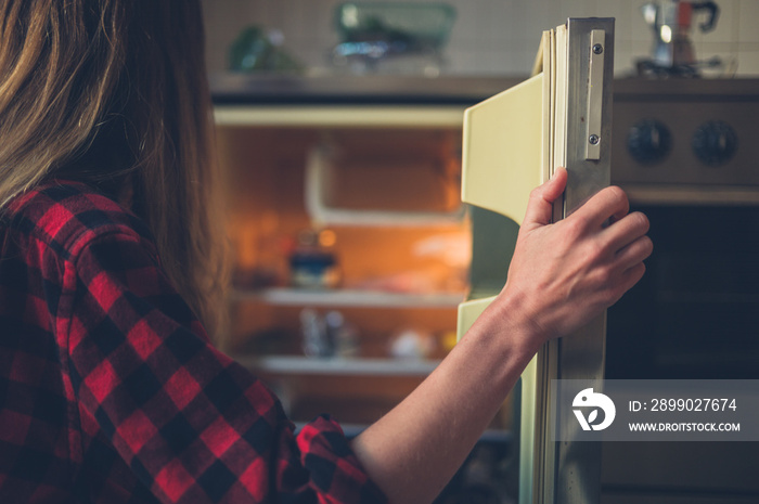 Young woman opening her fridge