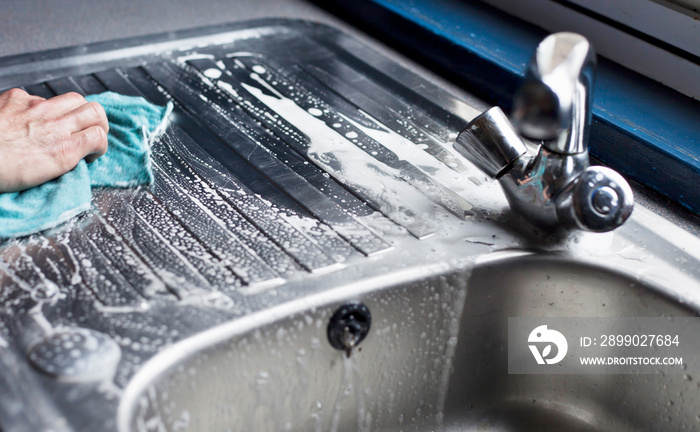 Cleaning the kichen sink with brush and cloth.