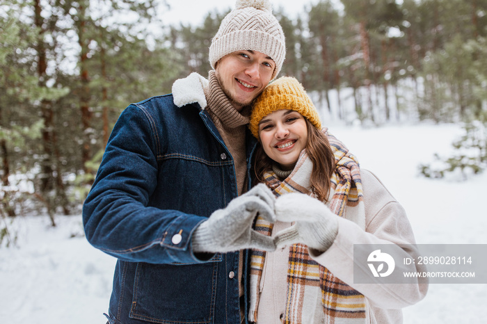 people, love and leisure concept - happy smiling couple making hand heart gesture in winter park