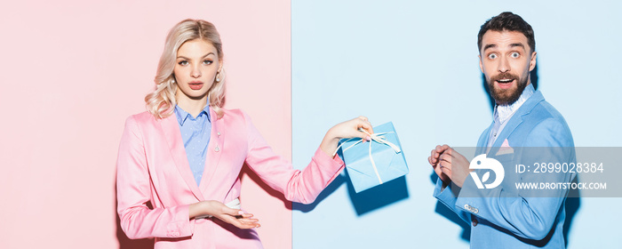 panoramic shot of shocked woman holding gift and handsome man on pink and blue background