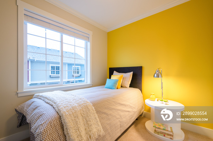 Modern yellow bedroom interior with blue and yellow pillows in a luxury house.