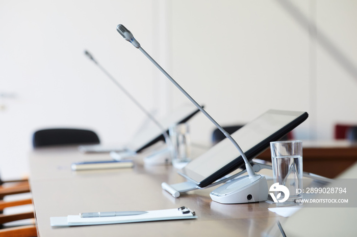 Image of empty table with computer and microphone at conference room