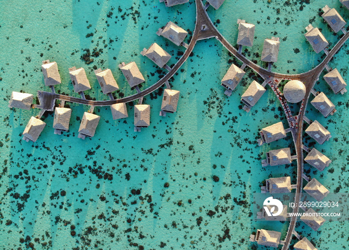 Aerial view of overwater bungalows with thatched roofs in the Moorea lagoon in French Polynesia