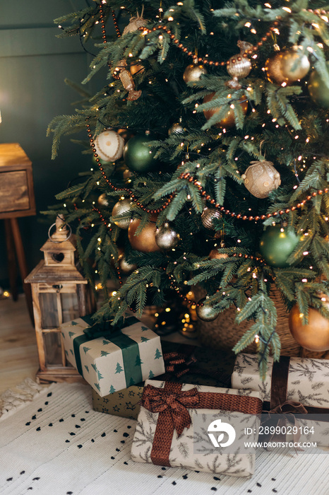 Green Christmas tree with emerald and bronze balls and craft gift boxes on the floor. Christmas inte