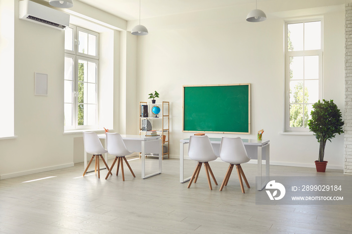 Modern empty classroom interior with desks, chairs and chalkboard. Light schoolroom with comfy furni